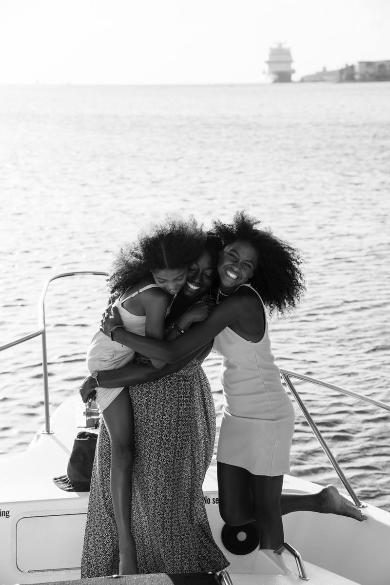 Mother and daughters hugging on the bow of the boat