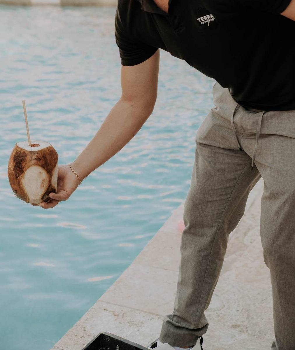 Terra Escapes team member serving a fresh coconut poolside