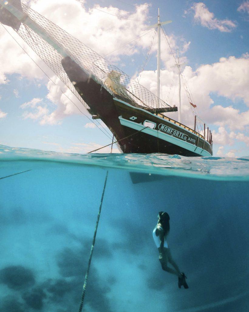 Snorkeller below a gulet anchored in clear water