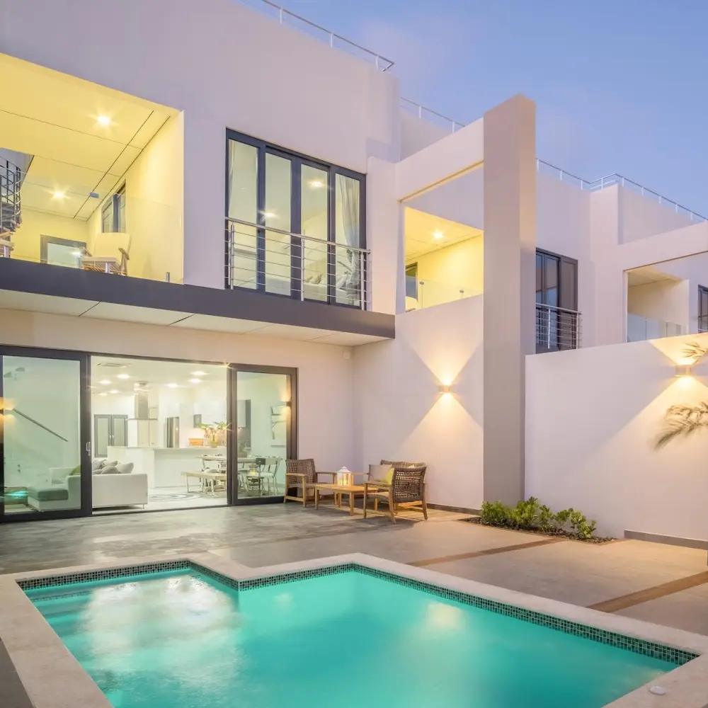 Modern villa with a private pool lit at dusk