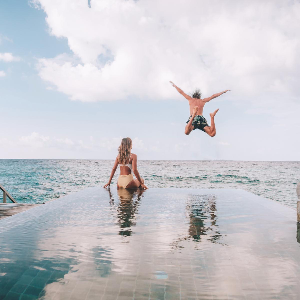 Couple at an infinity pool edge overlooking the sea